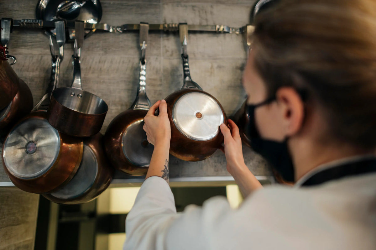 chef cuisinier dans un cuisine qui choisi une poêle en inox