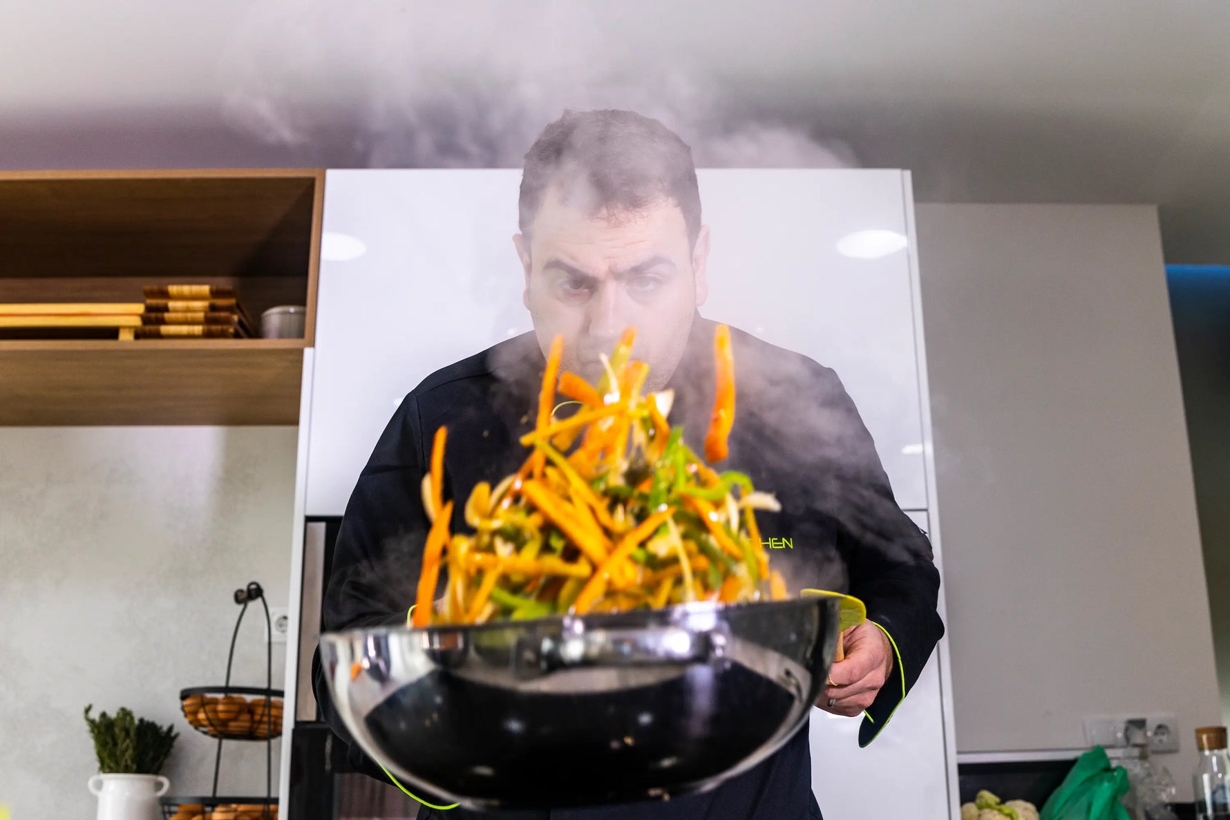 chef qui fais cuire des légumes  dans une sauteuse en inox  dans sa cuisine