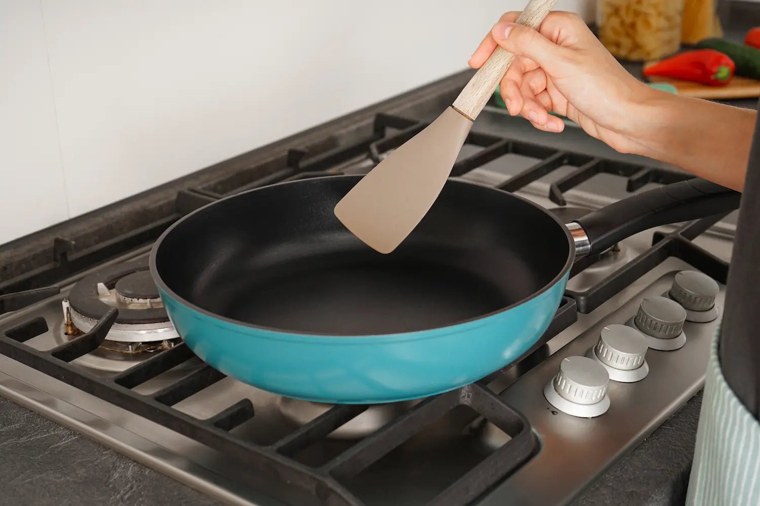 cuisine sur une cuisiniere a gaz avec une poele en teflon bleu
