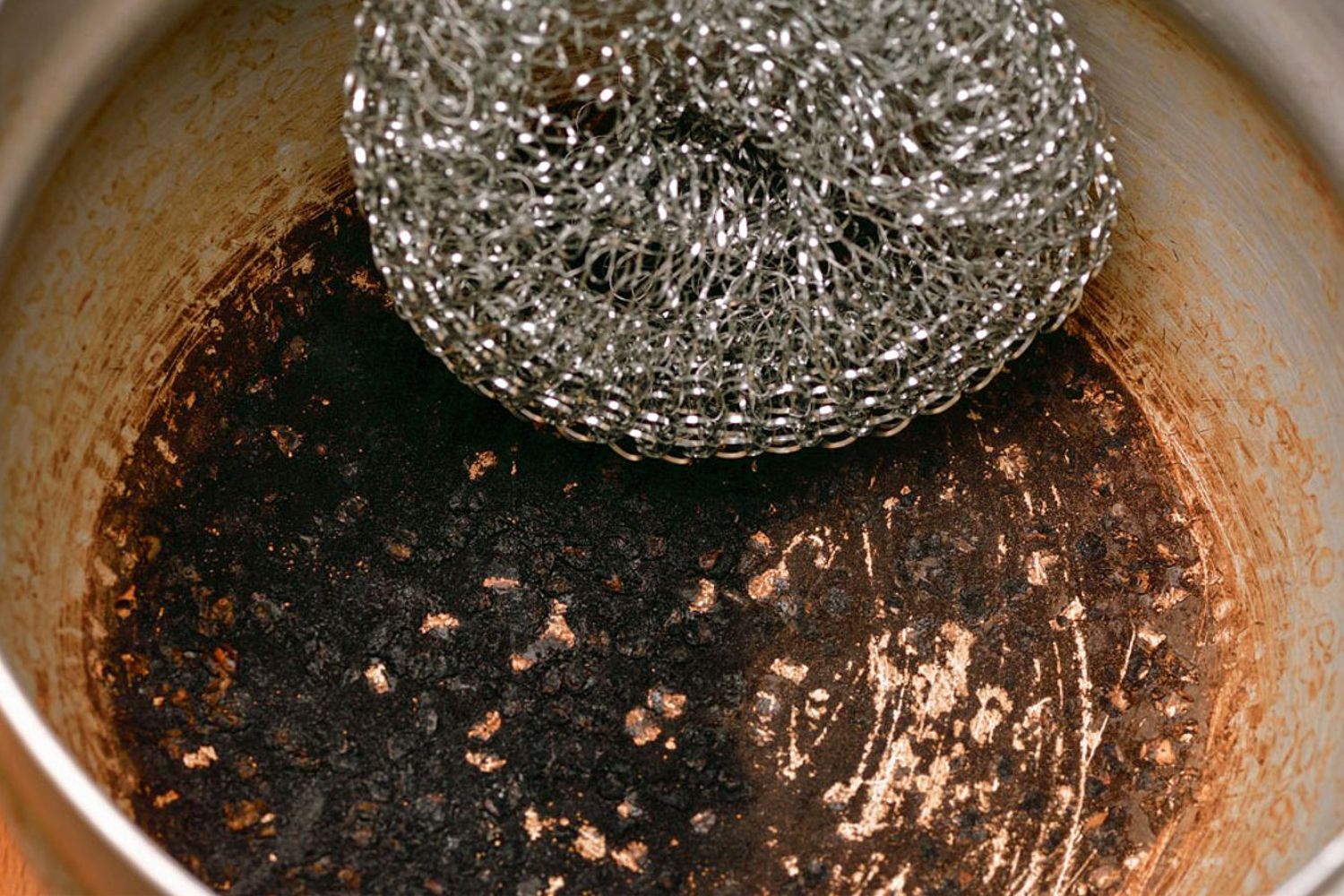 poêle en inox brulée avec un objet pour gratter celle-ci