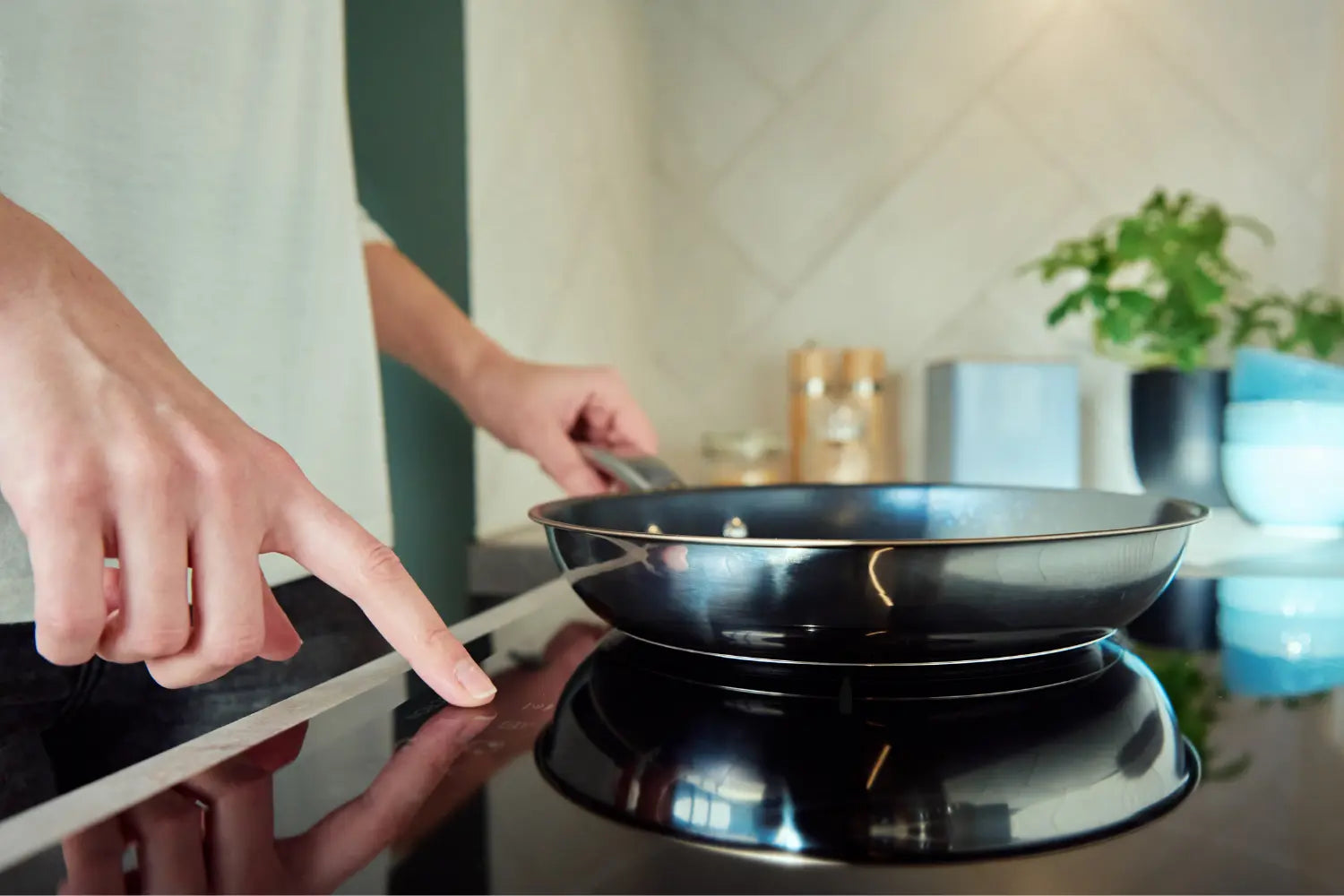 homme en tee shirt blanc qui utilise une plaque a induction pour faire à manger avec sa poele en inox
