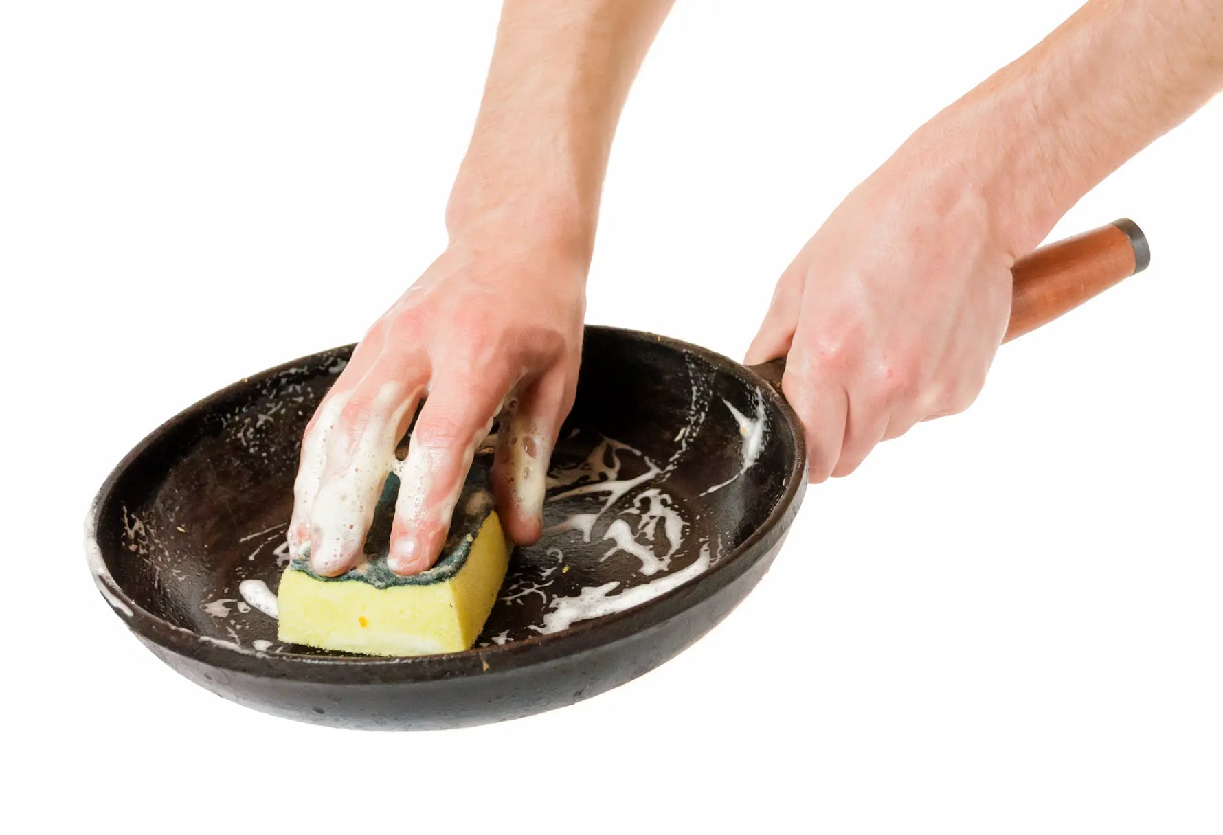 bras d'homme qui nettoie une poele avec une eponge et de la mousse