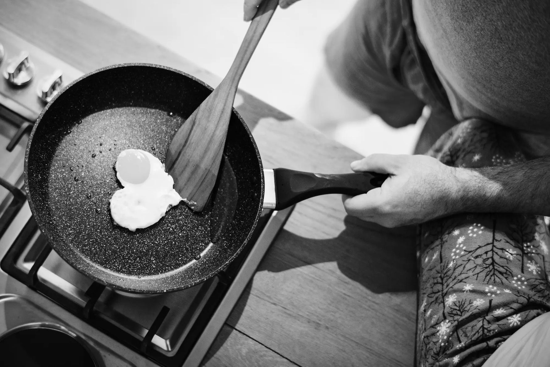 chef cuisinier entrain de faire cuir un oeuf en forme de coeur dans sa poele en pierre qui le retire de la poele avec sa spatule en bois