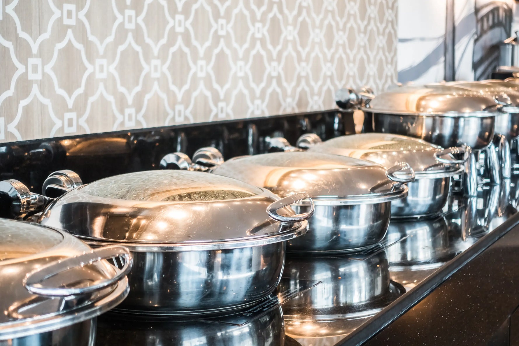 plusieurs sauteuses en inox avec leur couvercle déposées sur le buffet
