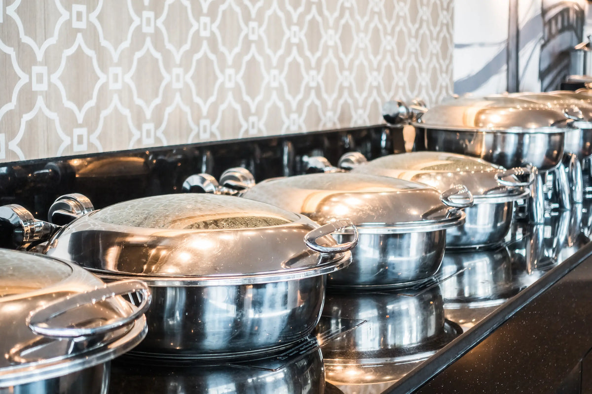 plusieurs sauteuses en inox avec leur couvercle déposées sur le buffet