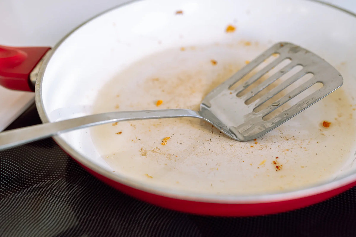 poele en ceramique blanche avec une spatule en inox sale