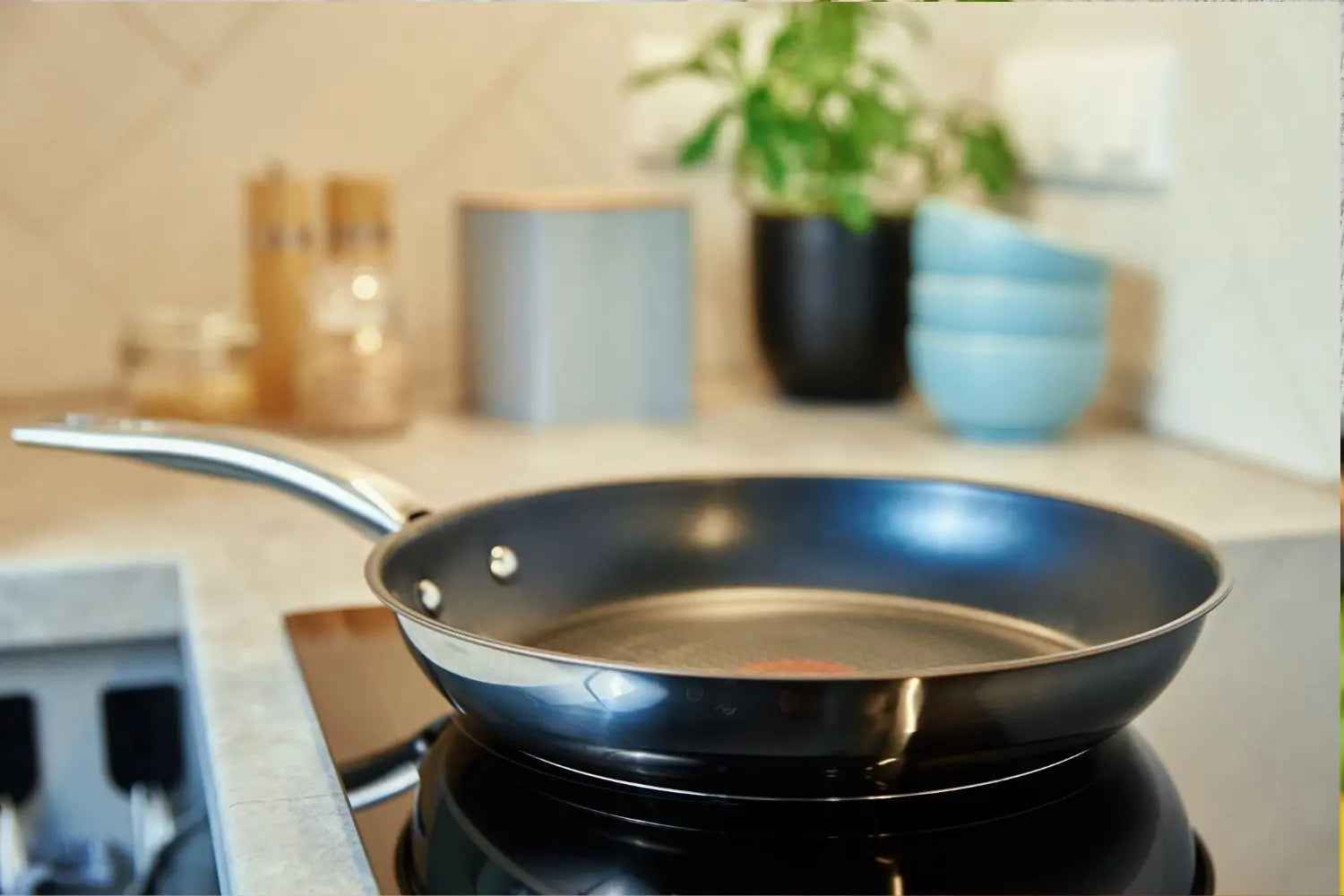 poele en inox sur une plaque à induction avec des bols en arriere plan