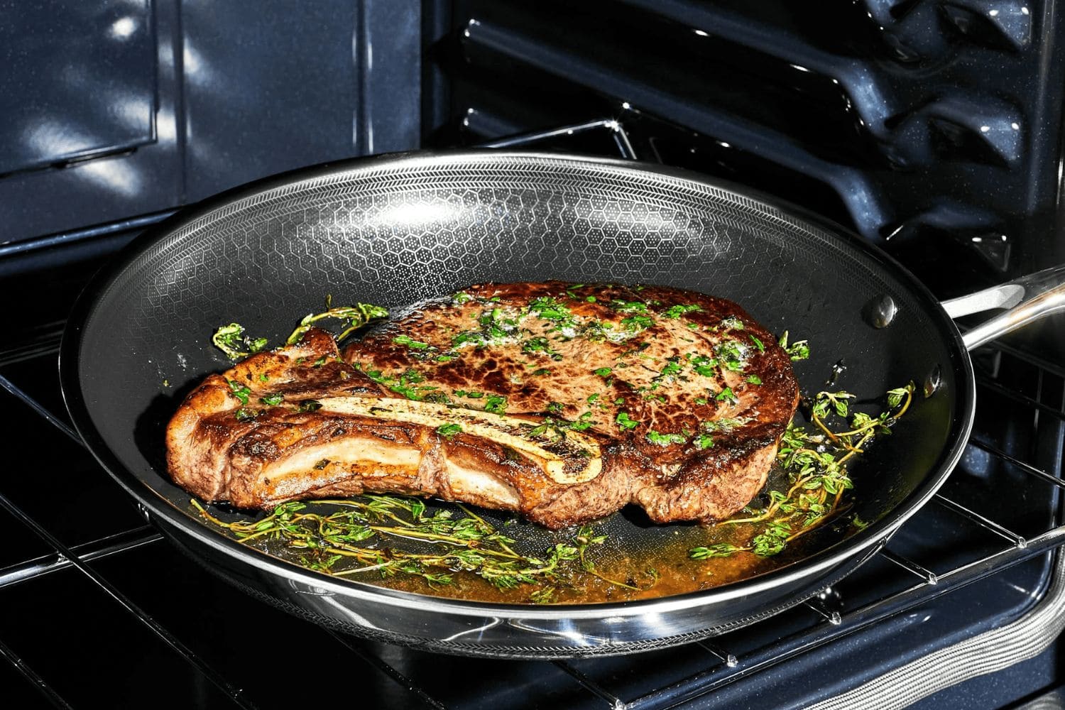 poêle en inox dans un four avec de la viande cuisson parfaite