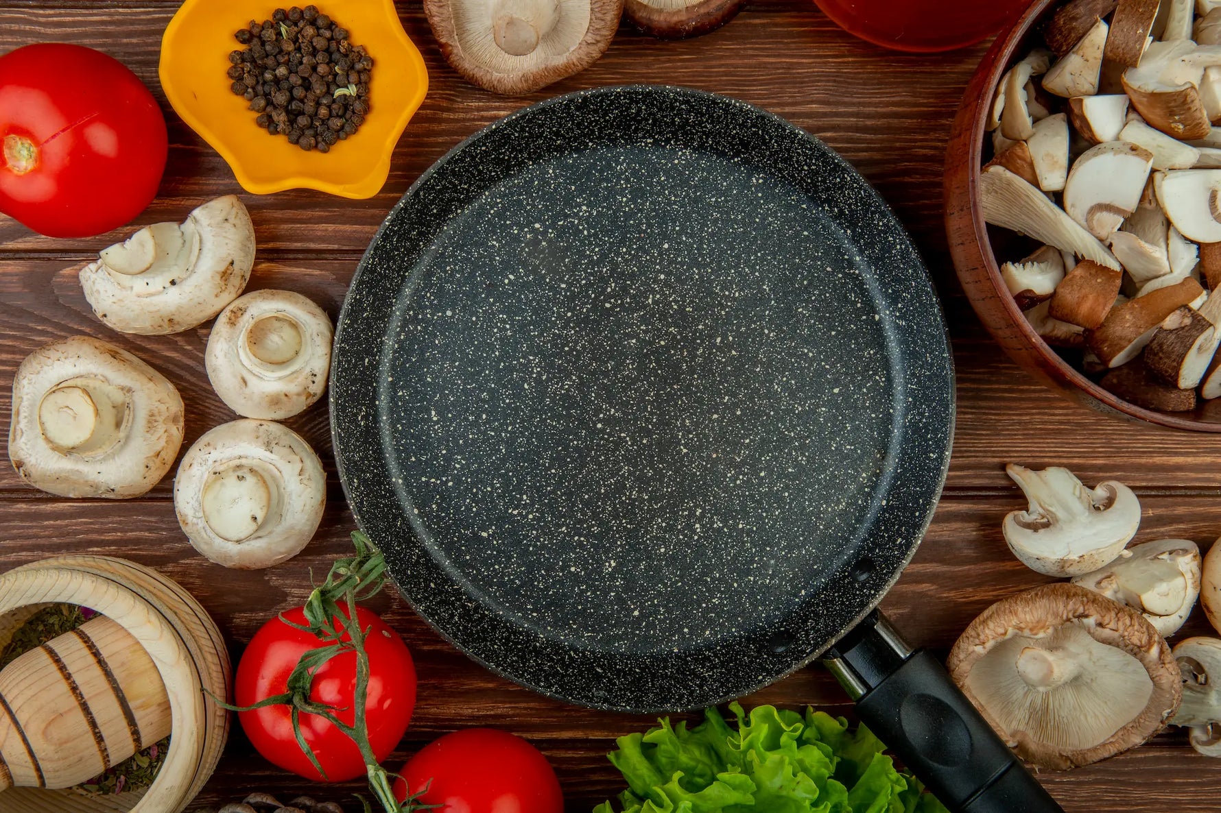 poele en pierre sur une table avec des champignons, tomates, poivrons, salades