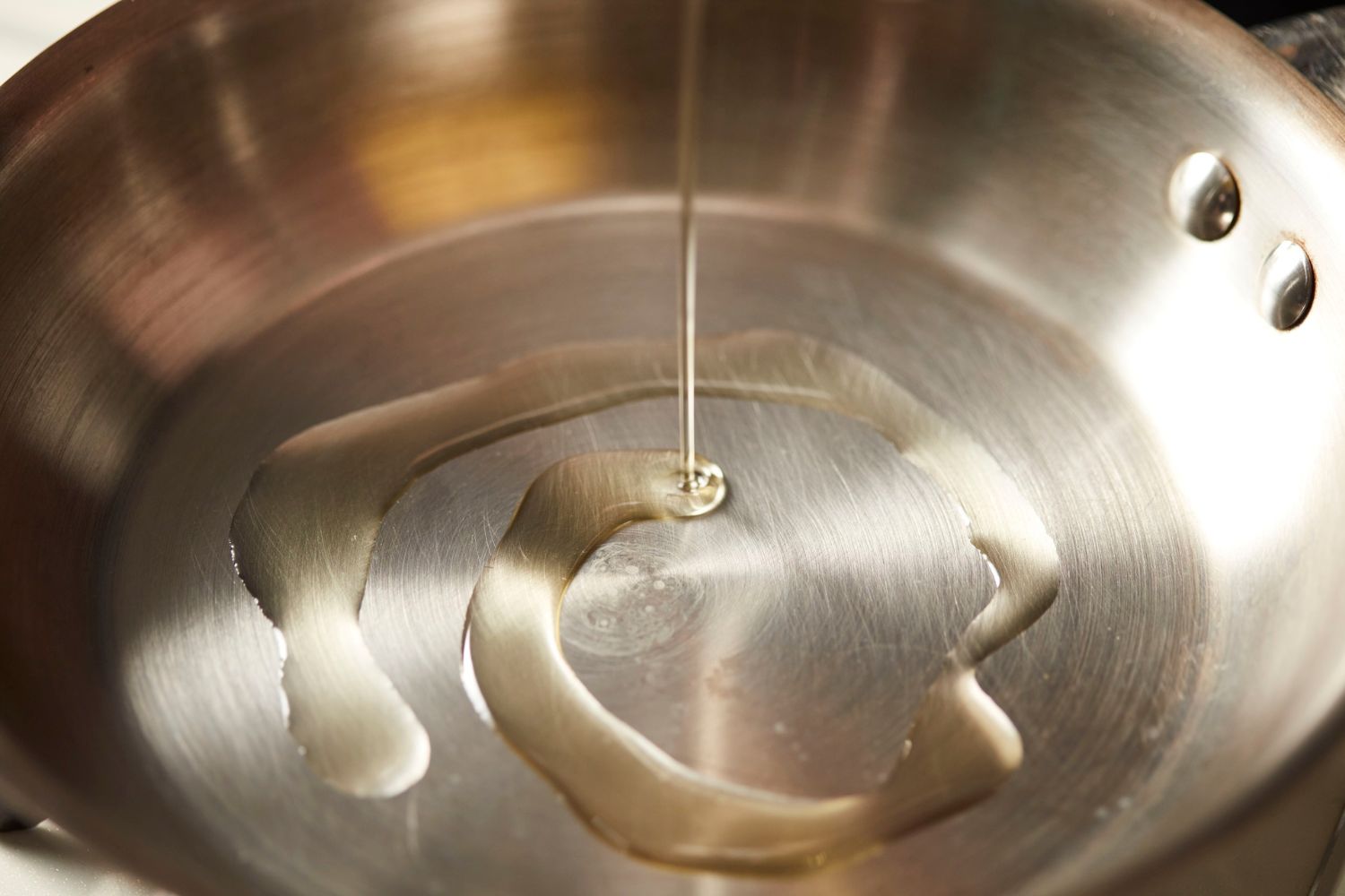 poêle en inox avec de l'huile d'olive dedans pour éviter que les aliments collent