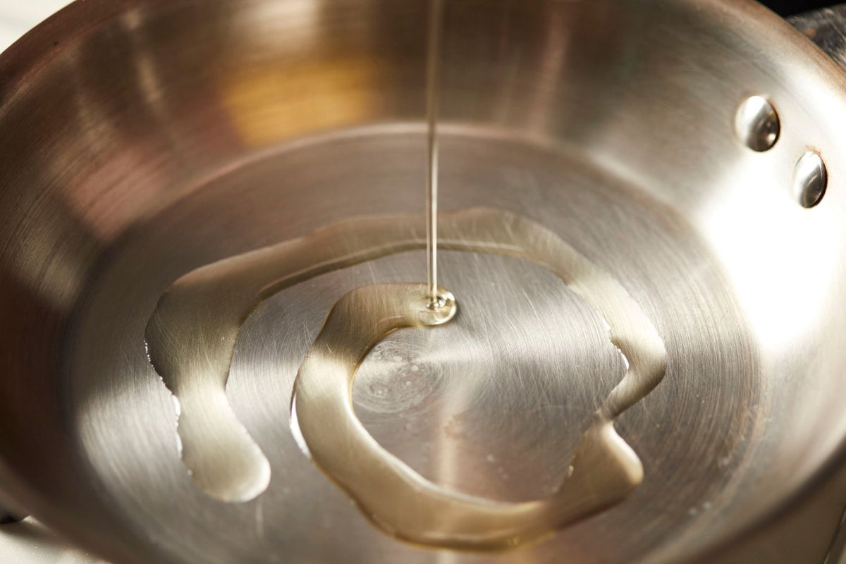 poêle en inox avec de l'huile d'olive dedans pour éviter que les aliments collent