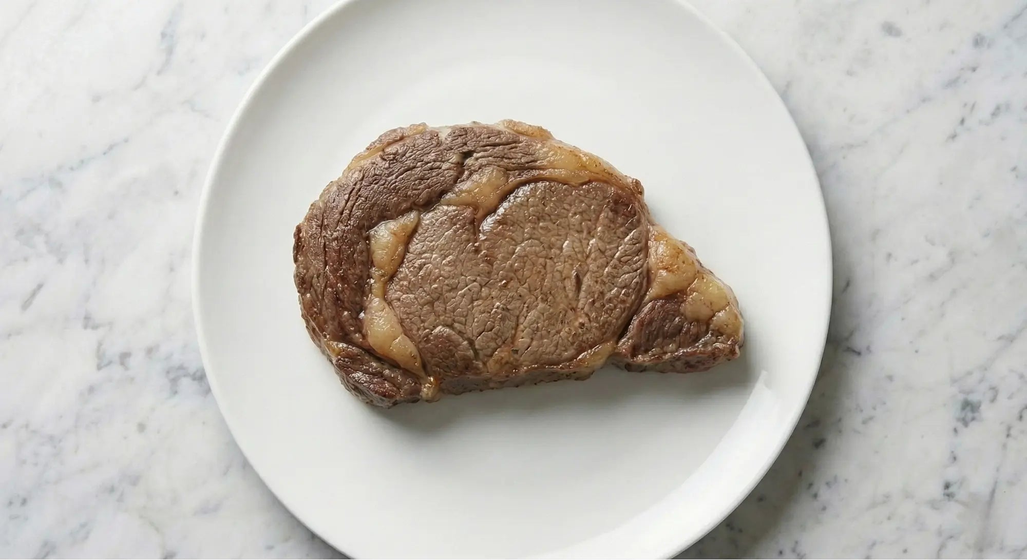 morceau de viande rouge dans une assiette cuite dans une poêle tefal